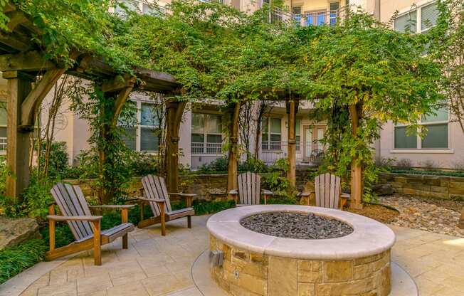 a fire pit with two chairs and a pergola in front of a building