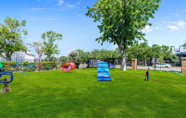 a large grassy area with a swing set and other playground equipment