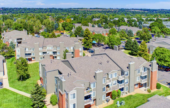 an aerial view of an apartment complex with green grass and trees
