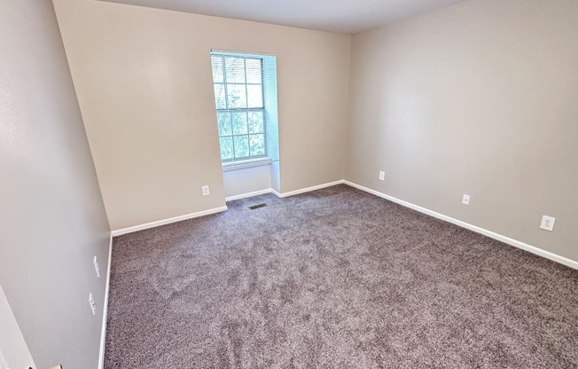 an empty room with carpet and a window