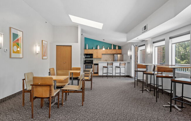 a dining room with tables and chairs and a kitchen in the background