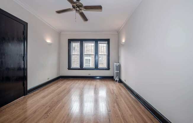 an empty room with hardwood floors and a ceiling fan