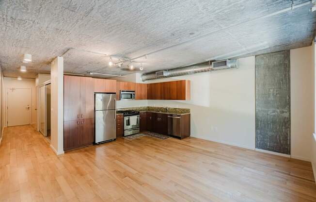 A kitchen area with wooden floors and a refrigerator.