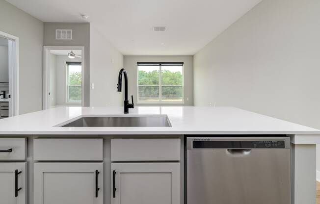 a large white kitchen with a stainless steel dishwasher and sink