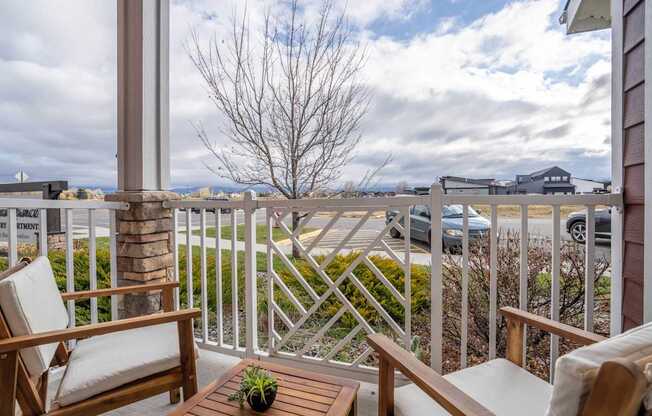 A balcony with a chair and table overlooking a parking lot.