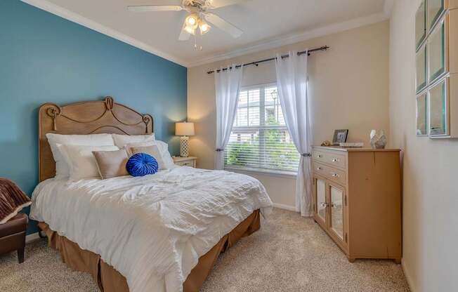 A bedroom with a bed, dresser, and window.