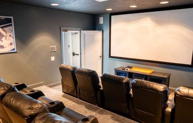 a screening room with leather chairs and a projector screen