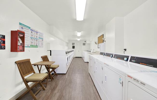 a washer and dryer room in a building with washing machines and two chairs at Camino de Oro Apartments, Torrance, CA