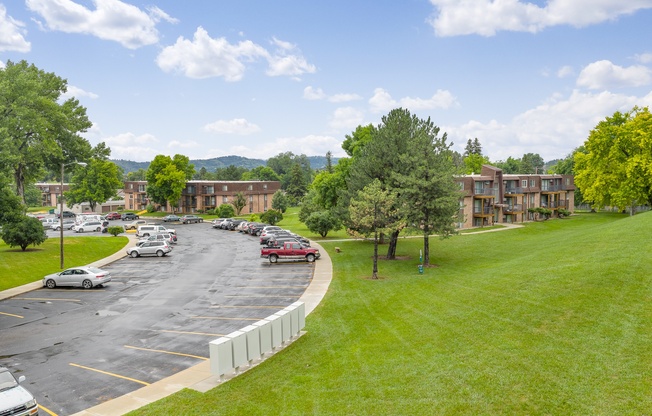 A parking lot with cars and a grassy area in front of a building.