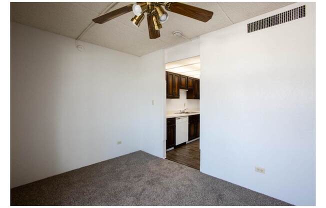 A room with a ceiling fan and carpeted floor.