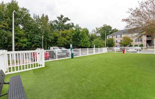 A white fence surrounds a green field.