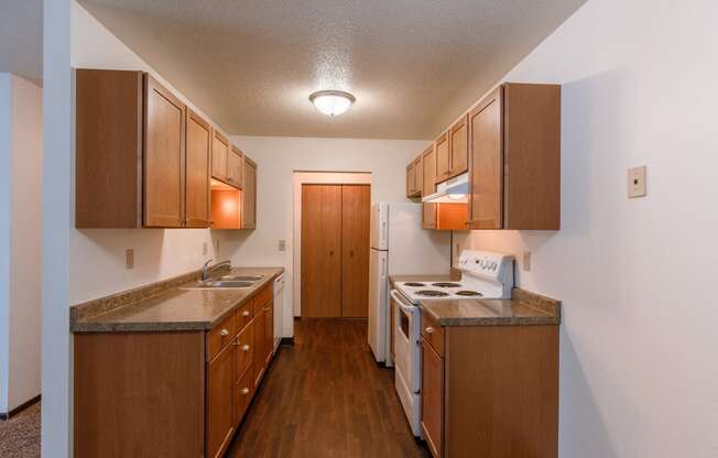 A kitchen with wooden cabinets and a white stove and refrigerator. Fargo, ND Long Island Apartments.