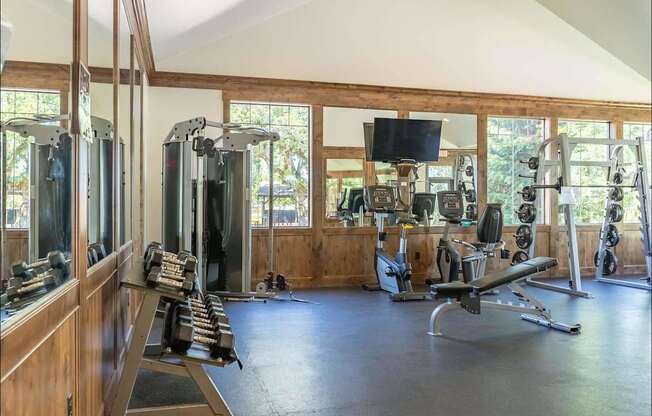 A spacious gym with a variety of equipment including treadmills, weights, and a television at Riverplace Apartment Homes, Oregon