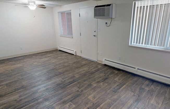 A room with wooden flooring and a window with blinds.