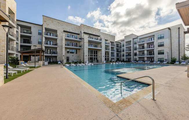 A large swimming pool is surrounded by apartment buildings.