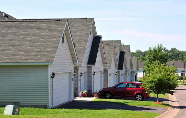 row of houses and garages with a red car parked in front of one