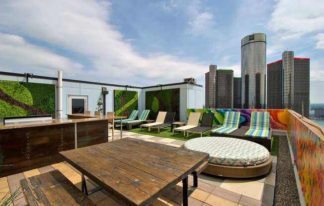 a rooftop terrace with furniture and a city in the background