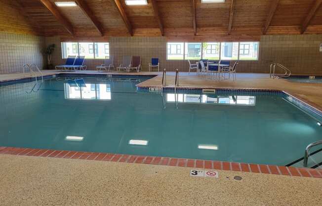 a large indoor swimming pool with chairs on the side