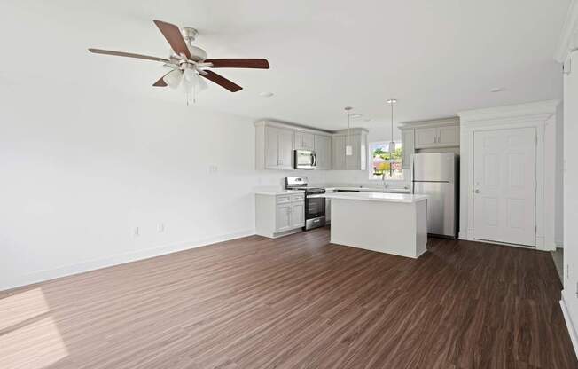 A kitchen with a ceiling fan and wooden floors.