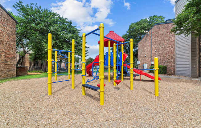 A playground with a red slide and yellow poles.