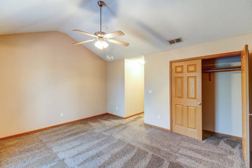 an empty living room with a ceiling fan and a door to a closet