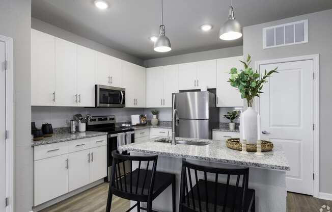 an open kitchen with white cabinets and a granite counter top