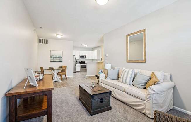 A living room with a couch, coffee table, and a dining table.