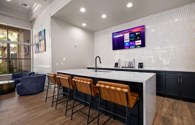 a kitchen with a counter and chairs and a tv on the wall