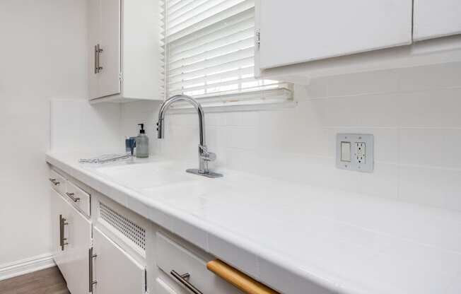 a white kitchen with white cabinets and a stainless steel sink