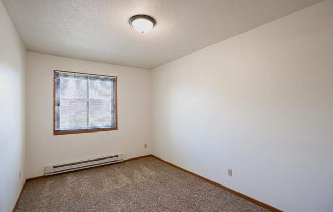 a bedroom with carpet and a window. Fargo, ND Southview Village Apartments