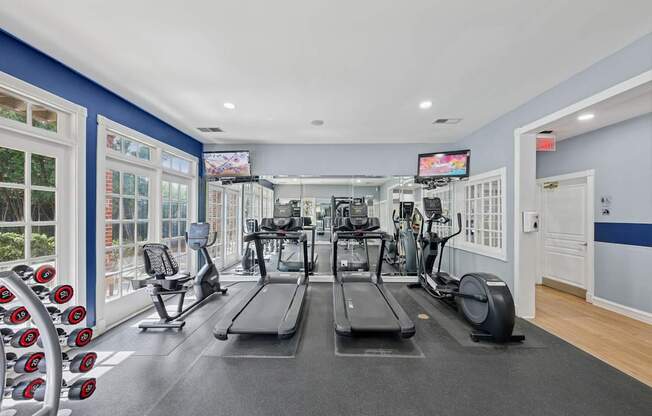 A gym with treadmills, elliptical machines, and dumbbells.