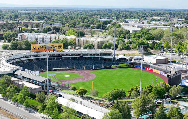 A large stadium with a green field in the center and a yellow sign that says "Catch the Game".