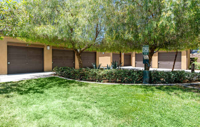 A parking lot with a green sign and a tree in front.