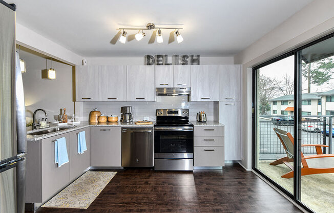 A modern kitchen with white cabinets and a wooden floor.