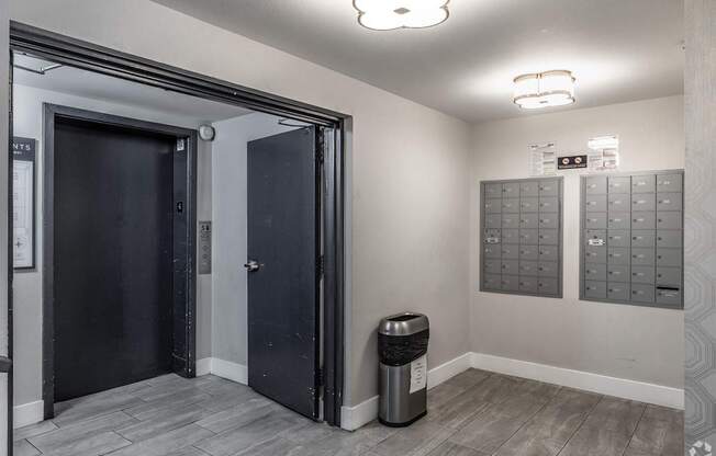 A room with a trash bin and a wall of mailboxes.