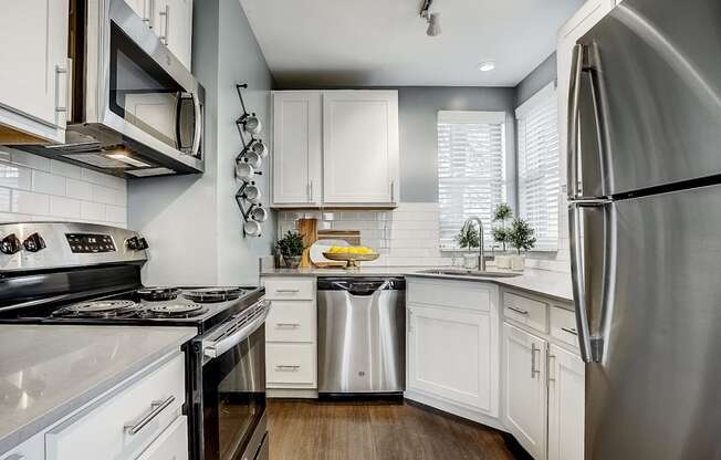 A modern kitchen with white cabinets and stainless steel appliances.