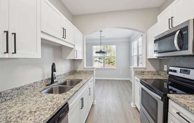 A kitchen with granite countertops and white cabinets.