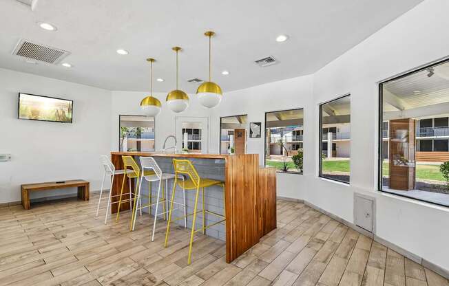 A kitchen with a bar area and yellow chairs.