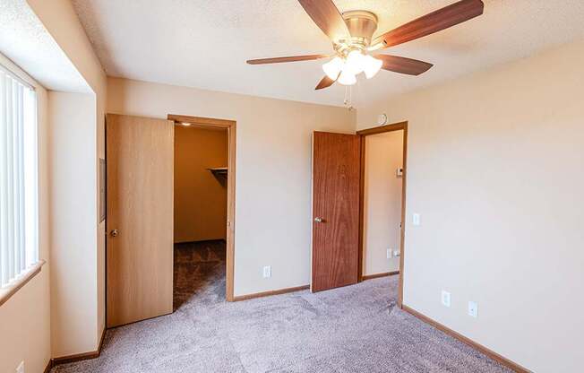 A room with a ceiling fan and carpeted floor.