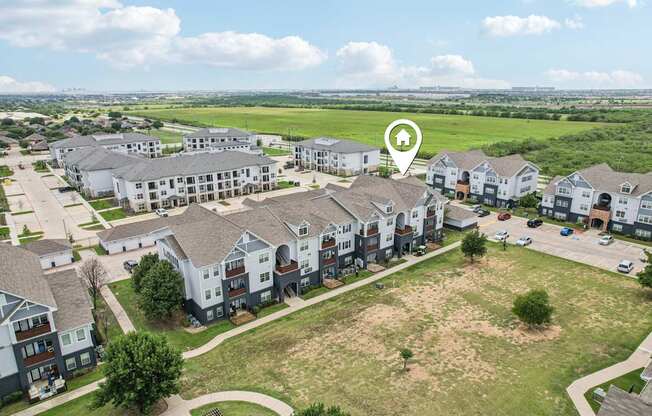 A bird's eye view of a residential area with apartment buildings and a large open field.