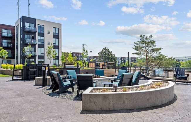 A modern outdoor seating area with a circular fire pit in the center.