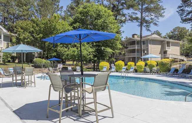 A blue umbrella is in front of a pool.