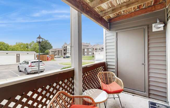 a balcony with two chairs and a door to a parking lot