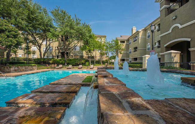 A large outdoor pool with a waterfall and a fountain.