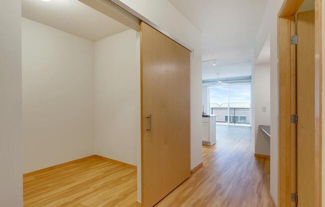 A hallway with a wooden floor and white walls.