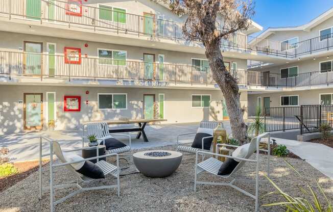 a courtyard with chairs and tables and a tree in front of a building