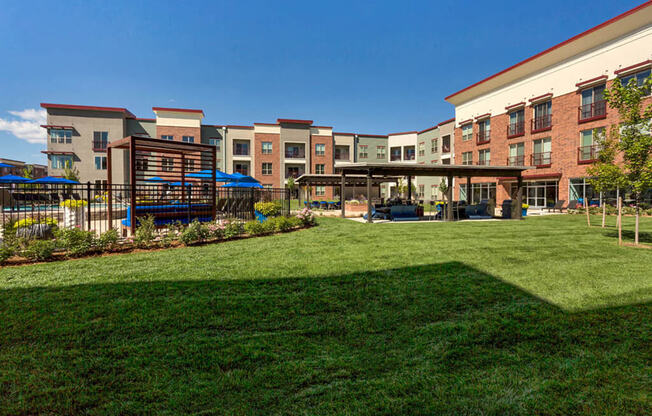 Westlake Greens Courtyard with grass, fenced in pool, pergola, and apartments behind