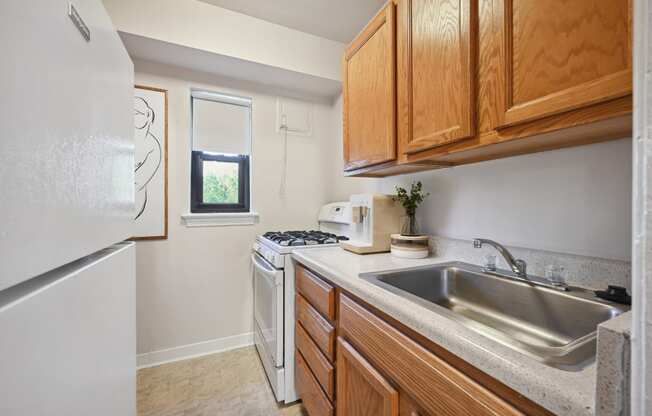 a kitchen with white appliances and wooden cabinets and a sink