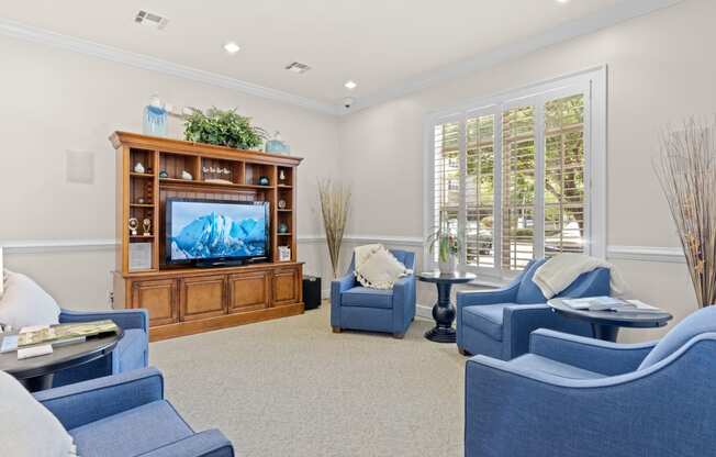 a living room with blue chairs and a television