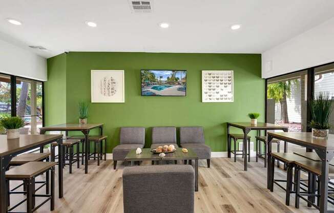A room with green walls and wooden floors has a couch, chairs, and a table.